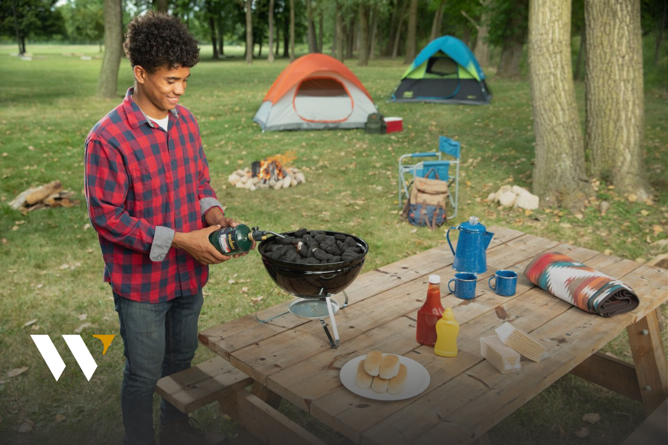 man at campsite lighting charcoal grill with propane torch